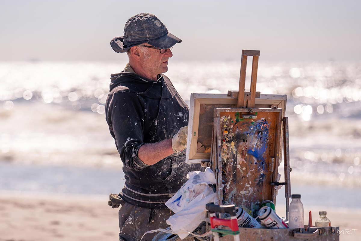 Peter Smit schilderend bij de fonkelende branding.